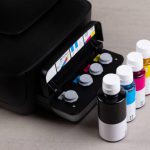 inkjet four-color printer with continuous ink supply and ink bottles for refilling on grey background close-up